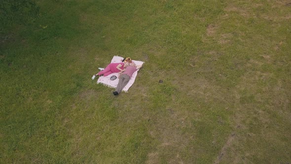 Family Weekend Picnic in Park. Aerial View. Senior Old Couple Lie on Blanket on Green Grass Meadow