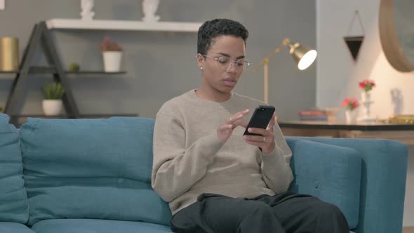 African Woman Using Smartphone While Sitting on Sofa