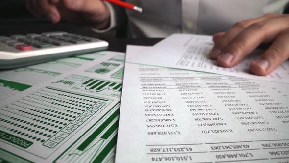 Accountant Analyzing Business Marketing Data on Paper Dashboard at Office Table