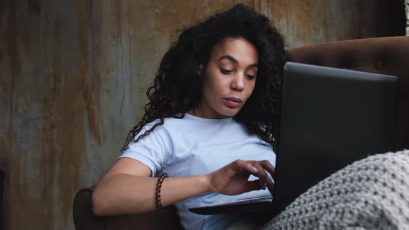 Young Attractive AfricanAmerican Woman Using Laptop Computer Sitting in Chair in Her Loft Bedroom