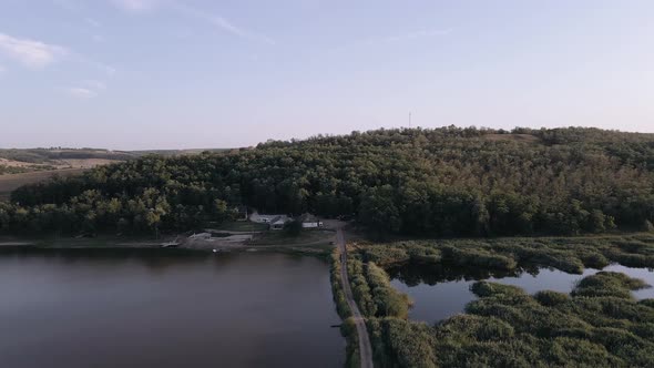 Video with the Drone Over a Lake. In Front of the Forest You Can See a Beautiful House.