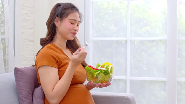 Pregnant Young Asian woman eat mixture of vegetables Fresh Salad at home