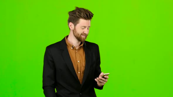 Guy Looks at the Phone in the Photo, and Has Fun. Green Screen