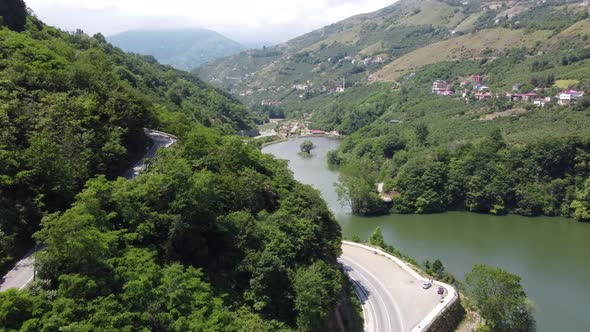 Mountain roads adjacent to the lake and clouds interfering with the tops of the mountains