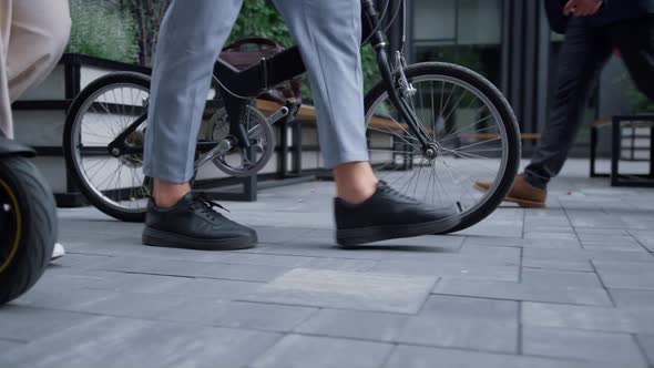 Closeup Managers Legs Walking with Bicycle Electric Scooter at Downtown Area