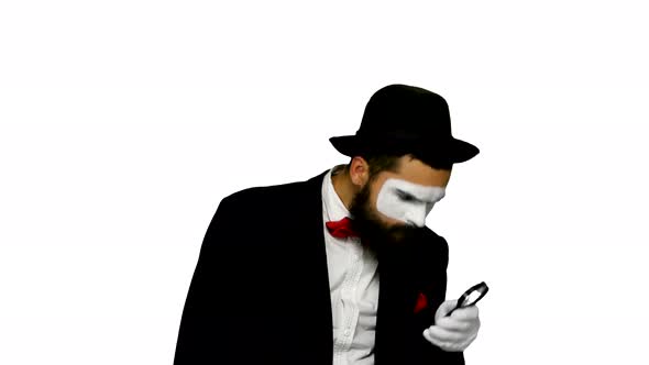 Man Mime Looks Uses Magnifier on White Background