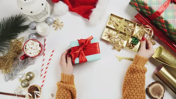 Woman Wrapping Christmas Present and Decorating Is By Wooden Star