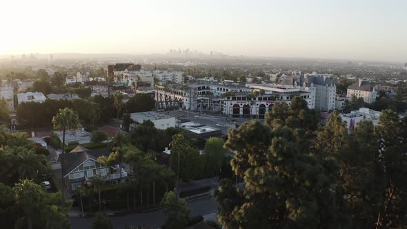 Aerial drone shot in West Hollywood looking out toward the tall skyscraper of downtown LA at sunset