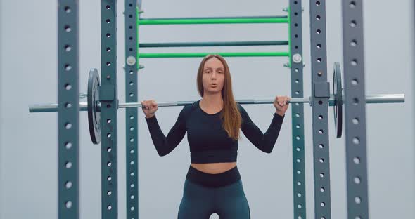 Young Beautiful Woman Doing Barbell Squats in the Gym