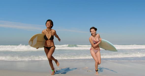 Young female friends running with surfboard 4k