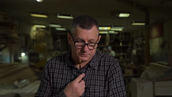 Engineer in Shirt Stands Against Background of Production with Sketch on Paper