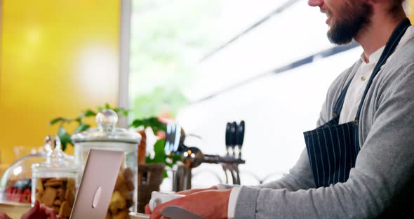 Waiter serving coffee to female costumer at counter