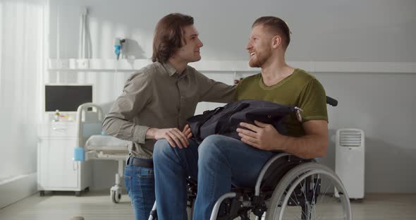 Young Man Taking Boyfriend in Wheelchair From Hospital