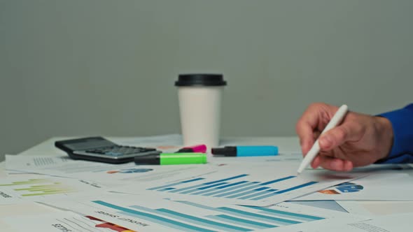 Businessman Sitting at His Desk in the Office Working with Company Strategy Documents Correcting