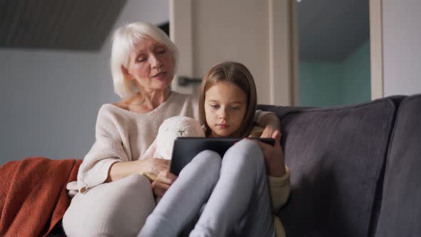 Surprised grandmother watching something on tablet with girl