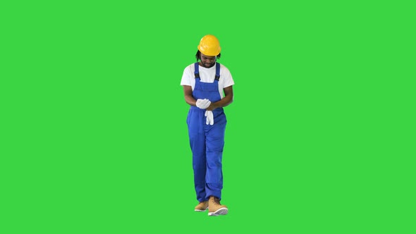 Construction Worker Putting on Gloves While Walking on a Green Screen Chroma Key