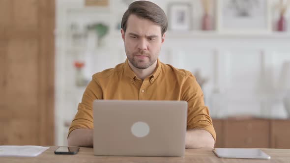 Young Man Working on Laptop in Office