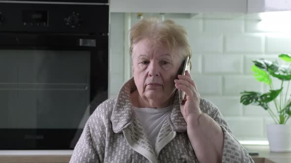 Headshot Video Portrait of Senior Woman Sitting at Home Holding Cell Phone Near Her Ear