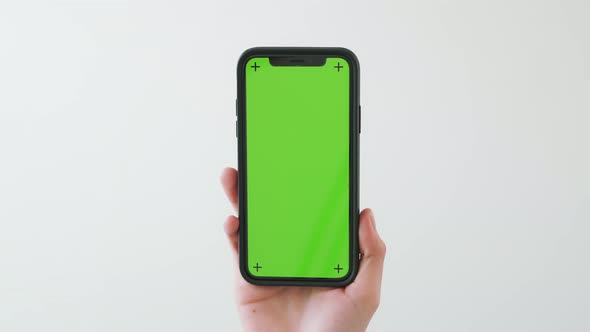 Hand holding smartphone with chroma key screen and showing on the white background.