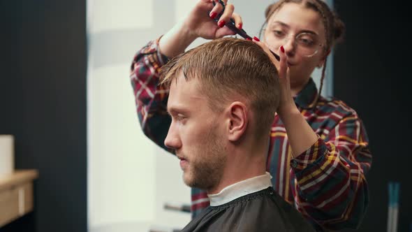 Barbershop: a woman barber cuts a client's man's hair