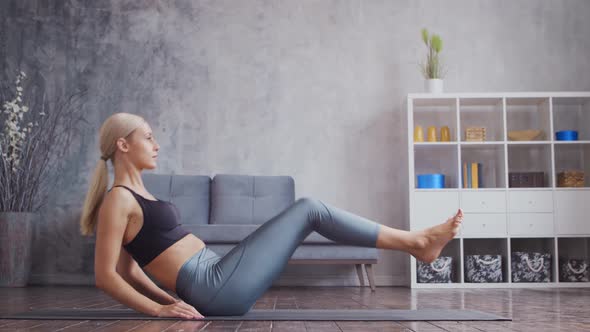 Young and sporty girl in sportswear is doing exercises in home interior.