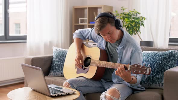 Man in Headphones with Laptop Playing Guitar