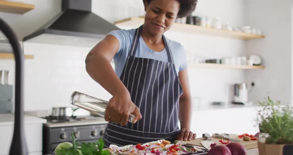 Happy african american woman preparing dinner in kitchen