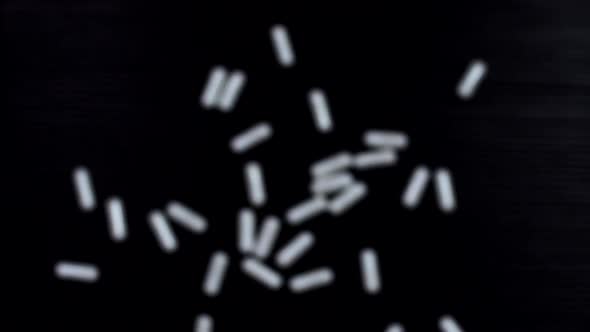White capsules fly up and hover in the air on a black background