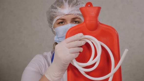 Closeup of a Female Doctor in a Hospital Holding a Hot Water Bottle or Enema