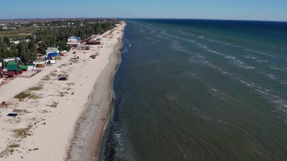 Beautiful flight in summer over the beach. People are resting near the sea. Houses for tourists.