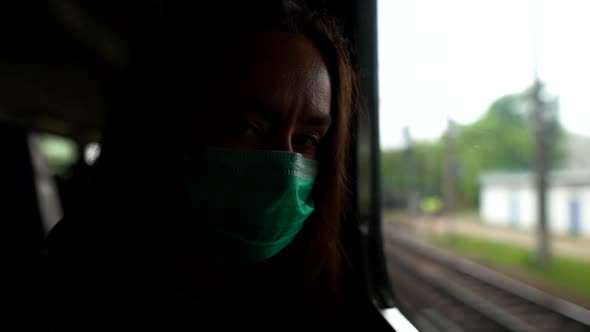 A Close-up Portrait of a Dark-haired, Middle-aged Woman Wearing a Medical Mask. She Rides the Train