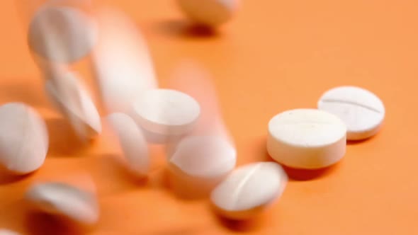 White Color Medical Pills Drops on Orange Background