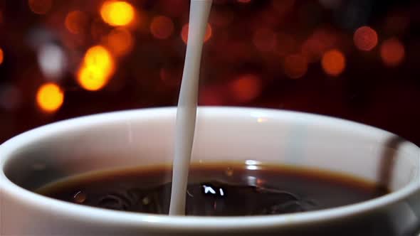 Milk Pouring in a Cup of Espresso. Side View. Closeup