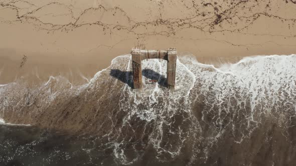 Aerial View of old broken pier made of cement in the middle of the ocean near Santa Cruz California.