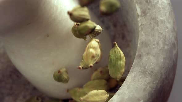 Granite Mortar and Cardamom Spice Species Falling in Slow Motion