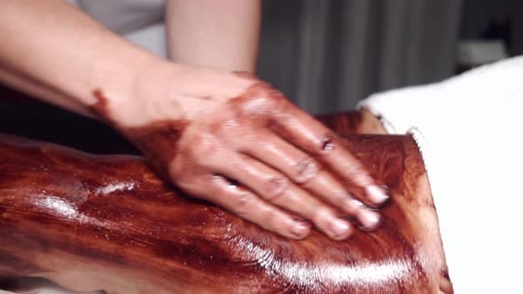 Closeup of Man Massaging Woman Legs Using Mask