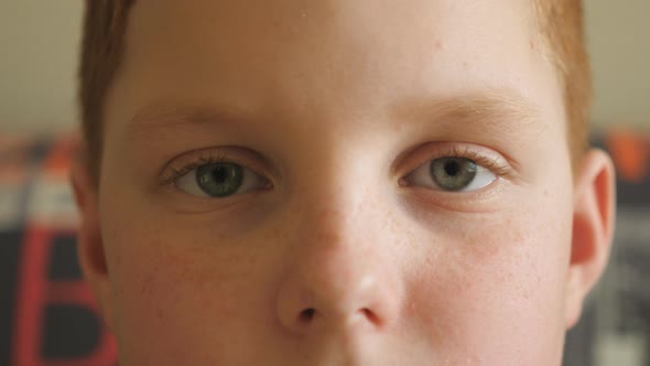Close Up Blue Eyes of Small Red-haired Boy Blinking and Looking Into Camera with a Tired Sight