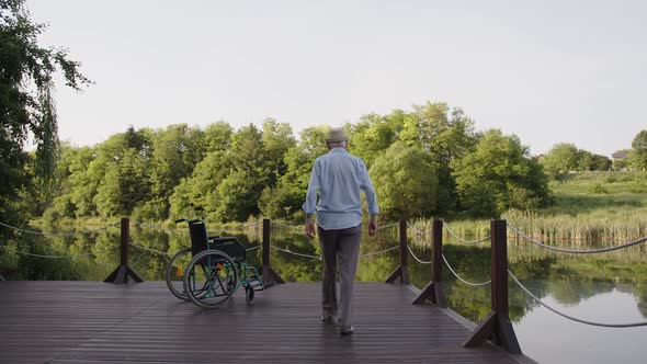 Old Man in White Shirt Slowly Walks to Lake