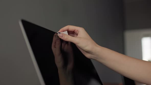 A Girl Puts a Sticker on a Camera on a Laptop
