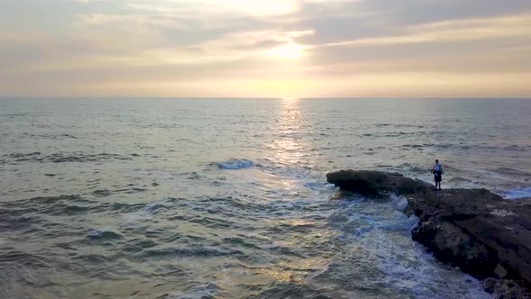 Fisherman on the Rocky Shore of a Stormy Sea at Sunrise. Aerial Survey