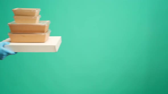 People's Hands Passing Each Other Packed Boxes with Food Delivery Against Mint Studio Background