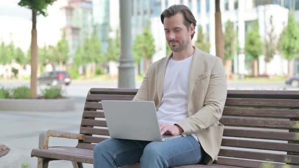 Young Man Using Laptop While Sitting on Bench