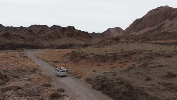 Car Goes on a Dirt Road Among the Mountains