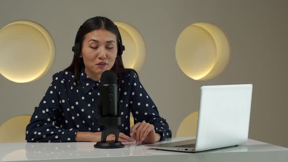 Asian Woman Recording a Podcast on Laptop Computer with Microphone While Online Live Streaming