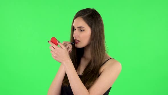 Girl Paints Her Lips Looking in Red Mirror. Green Screen