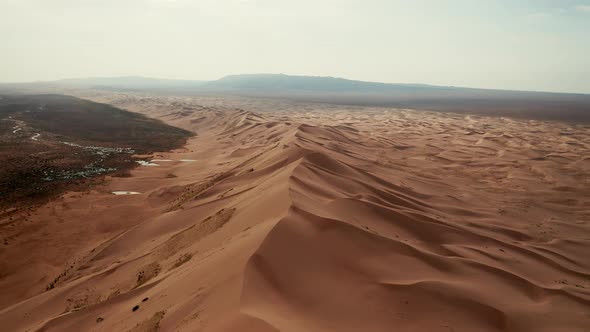 Aerial view of the sand dunes in the Gobi desert, birds flying across in the distance a late morning