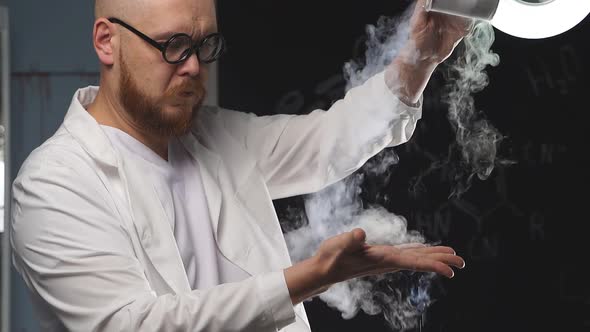 A Male Chemist Pours Liquid Nitrogen on His Hand Which Turns Into White Vapor