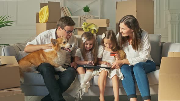 A Happy Family Uses a Tablet for Online Shopping Sitting on the Couch at Home