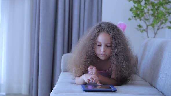 Curious Cute Girl Preschool Child Using a Digital Tablet Technology Device Looks telephone