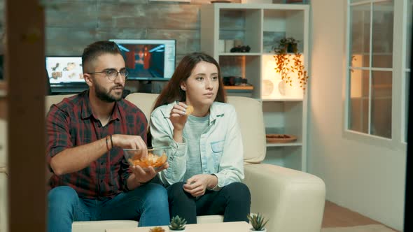 Young Couple Sitting on the Couch and Watching Television